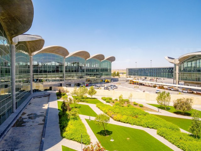 Glass-paneled terminal building and greenery at Queen Alia International Airport in Jordan