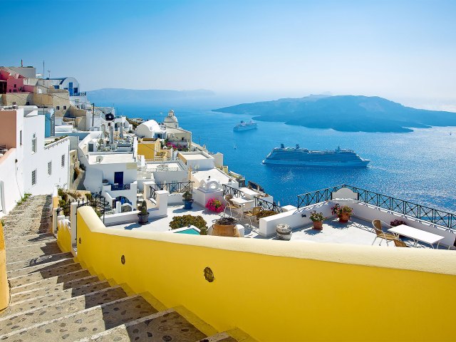 Steps leading past whitewashed homes overlooking the sea in Fira, Greece