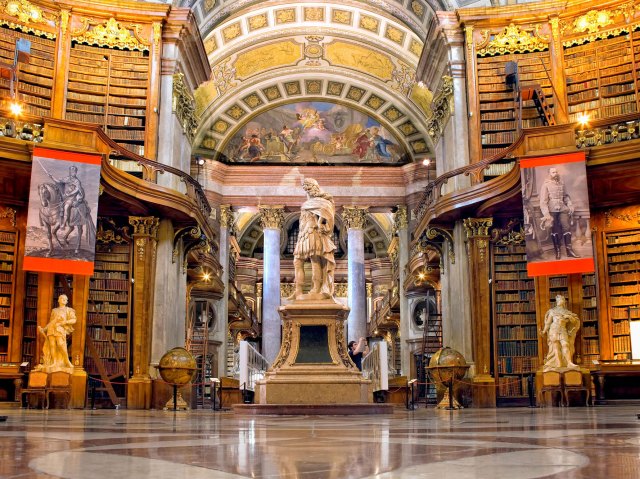 Statues and two stories of bookshelves inside the Austrian National Library in Vienna