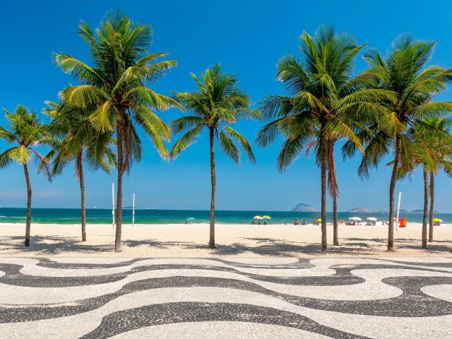 Palm trees, sand, and iconic wavy boardwalk at Copacabana Beach in Rio de Janeiro