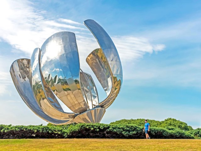 Person walking by flower-shaped "Floralis Generica" statue in Buenos Aires, Argentina
