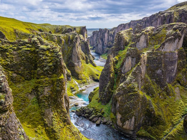 River running through dramatic, green Fjaðrárgljúfur canyon in Iceland