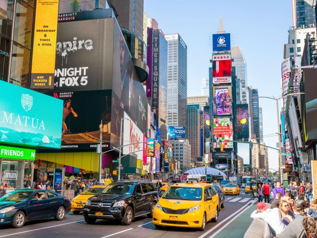 Street filled with cars, pedestrians, and billboards in Times Square, New York