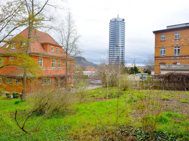 Garden surrounded by homes and a modern glass high-rise in Jena, Germany