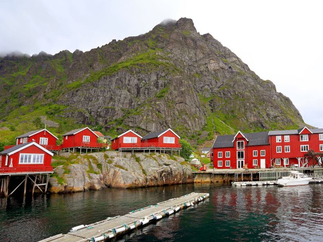 Red homes along dock, framed by mountains, in the village of Å, Norway