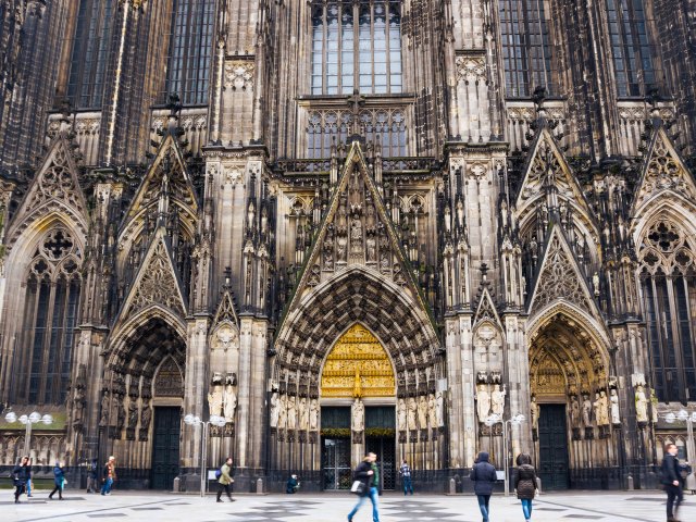 People passing by ornate Gothic facade of the Cologne Cathedral