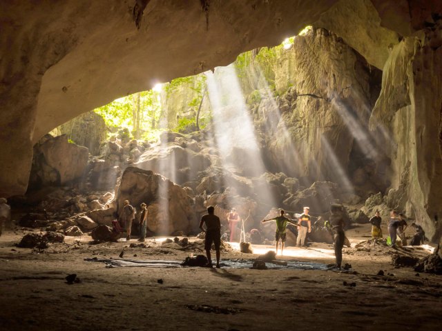 People in sunlight-filled cave in Taman Negara, Malaysia 