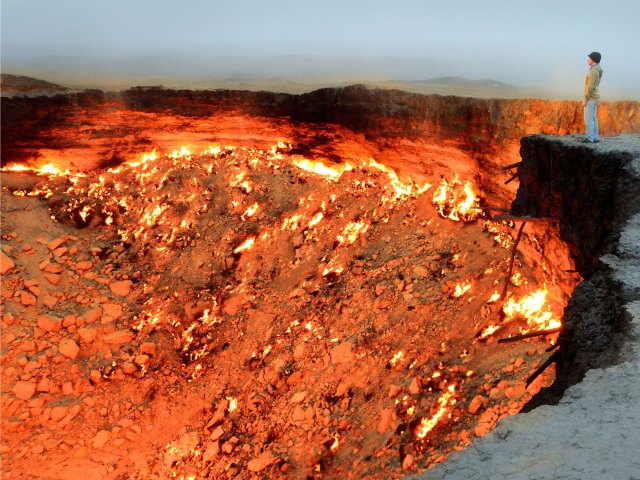 Person standing over the burning Darvaza Gas Crater in Turkmenistan's Karakum Desert