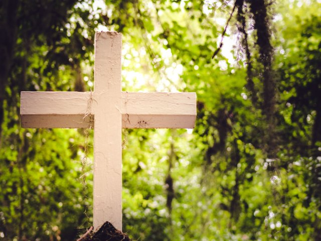 White wooden religious cross in the forest
