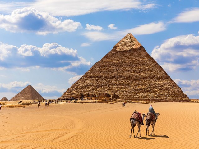 Camels standing in desert in front of Great Pyramid of Giza in Egypt