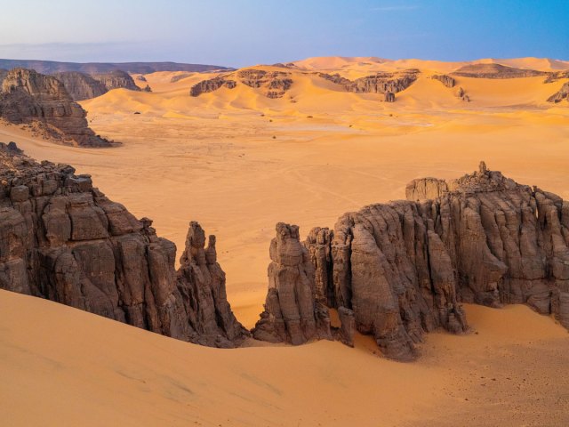 Rock formations surrounding sand dunes in the Sahara Desert