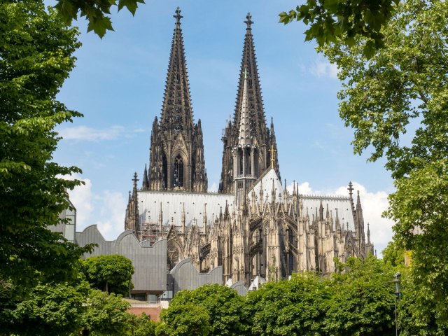 Twin spires of Cologne Cathedral in Germany, seen between trees