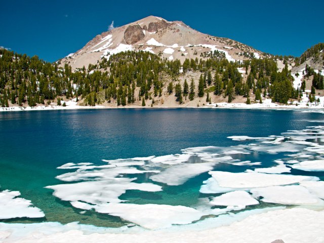 Ice-filled lake and snow-capped peak in Lassen Volcanic National Park in California