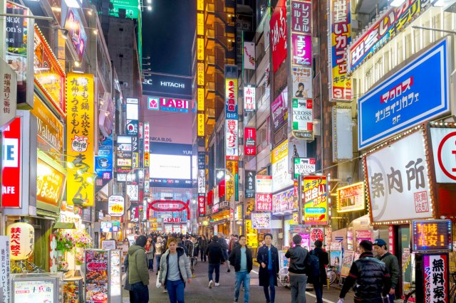 Crowded street lit with neon billboards in Tokyo, Japan