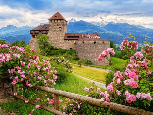 Colorful flowers framing stone building in the mountains of Liechtenstein