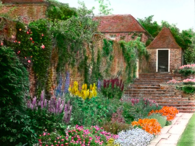 Colorful flowers along brick wall at Great Maytham Hall Garden in Kent, England