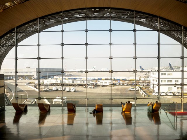Passengers lounging in terminal overlooking airfield at Paris Charles de Gaulle Airport