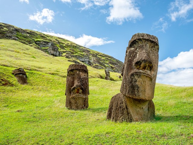 Giant half-buried Moai statue on grassy hill on Easter Island