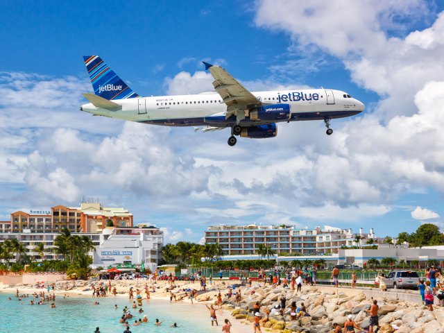 JetBlue Airways airplane landing over beach crowded with people