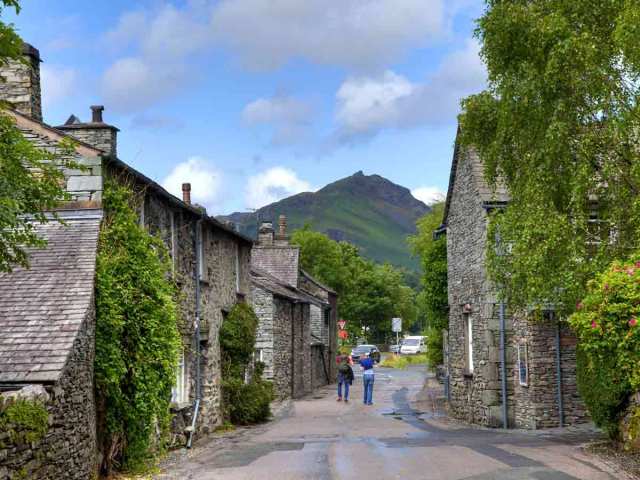 People walking on narrow street lined with homes in Grasmere, England
