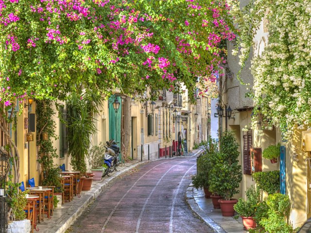 Narrow street lined with homes and flowering plants in Athens, Greece