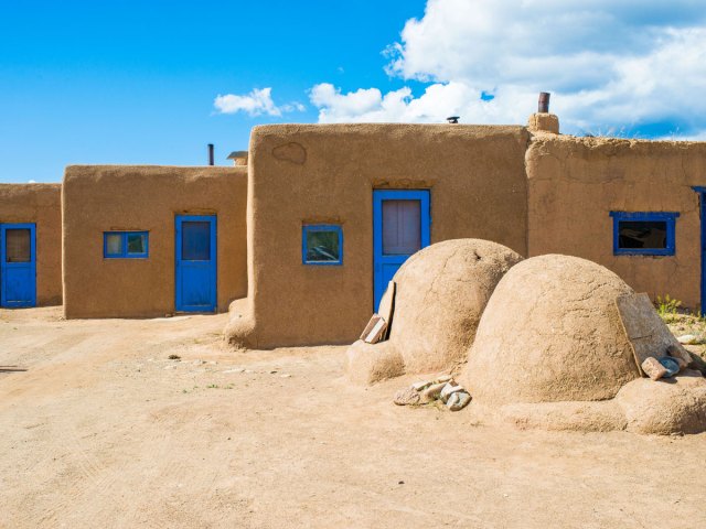 Adobe dwellings with blue doors and blue-trimmed windows in Taos Pueblo, New Mexico