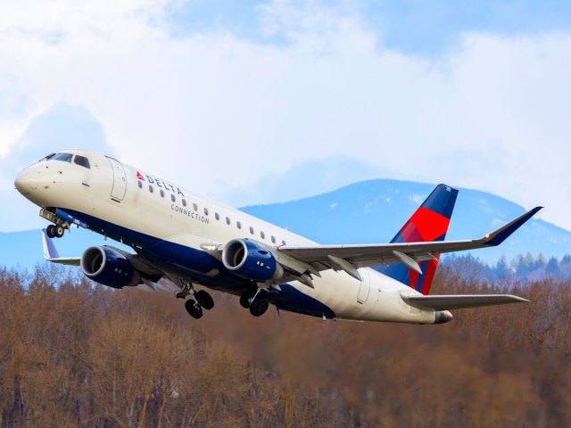 Delta Air Lines airplane taking off with mountain in background