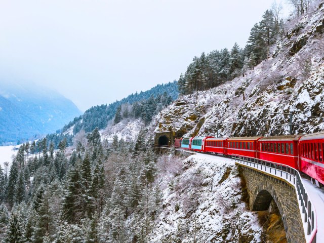 Red train cars on snowy mountainside in St. Moritz, Switzerland