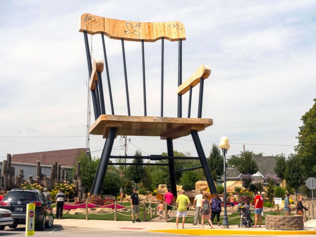 People standing under statue of giant rocking chair in Casey, Illinois