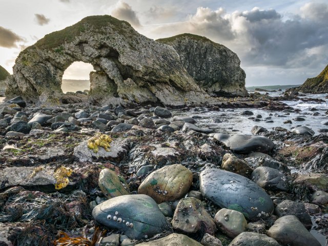 Natural stone arch and rocky coastline of Ballintoy, Northern Ireland