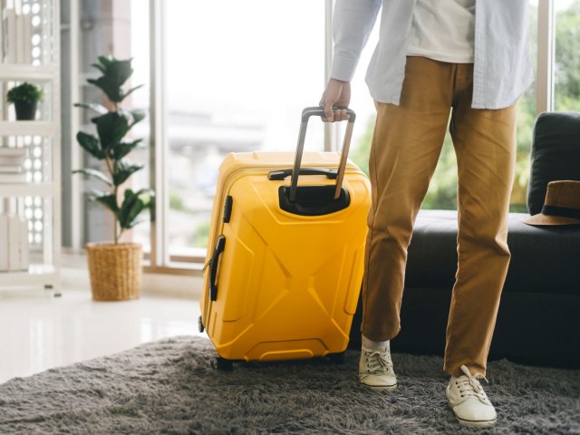 Person rolling yellow suitcase in home