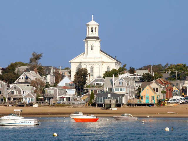 Boats moored in Mystic, Connecticut's harbor with church and other buildings in background