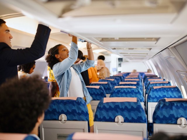 Passengers stowing carry-on luggage on airplane