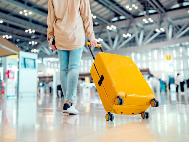 Traveler rolling bright yellow suitcase through airpoirt