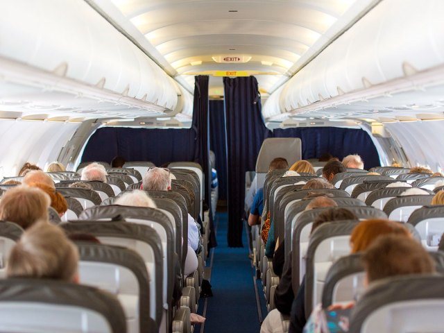 Passengers seated in airplane cabin, viewed from behind