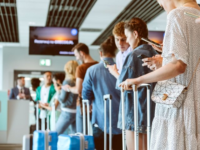 Travelers lined up at airport counter with luggage