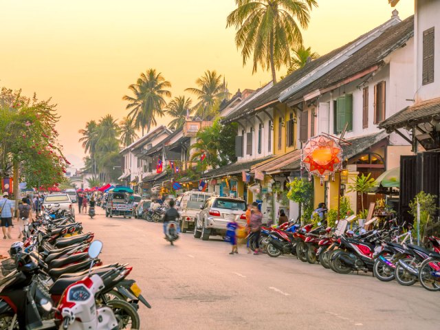 Street in Laos lined with motorbikes at sunset