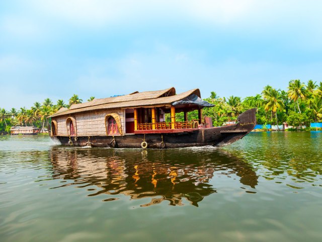 Boat on canal lined with palm trees in Alappuzha, India
