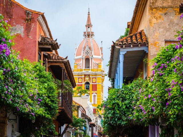 Brightly painted church framed by buildings covered in flowering plants in Cartagena, Colombia