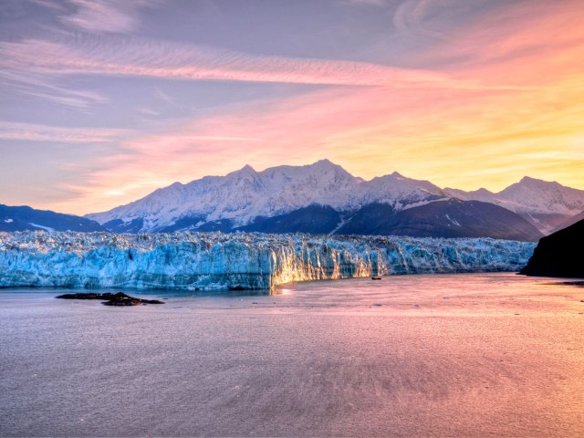 View of Alaska's Hubbard Glacier across body of water at sunset