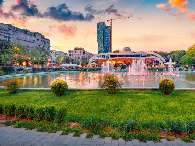 Fountain in Tirana, Albania, surrounded by city skyline at dusk