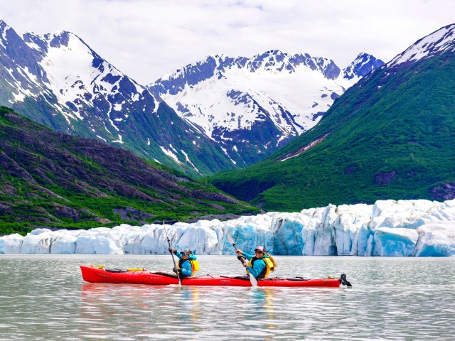 Couple kayaking next to glacier in Alaska