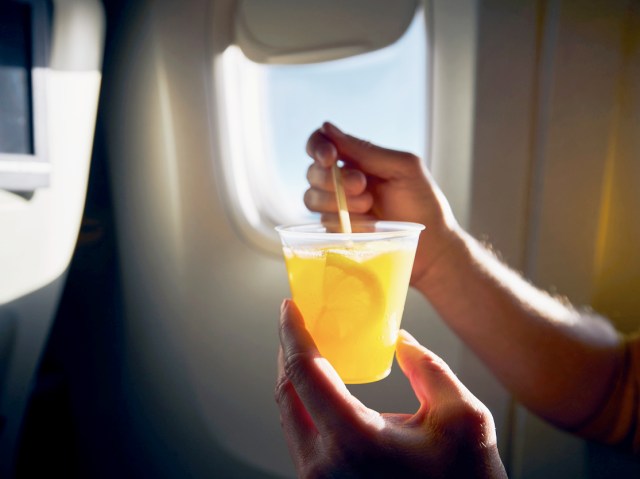 Close-up view of passenger holding drink in airplane seat