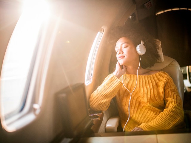Traveler wearing sweater and headphones in airplane seat