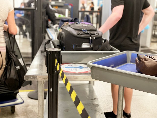 Close-up view of passengers placing luggage in bins to go through airport security
