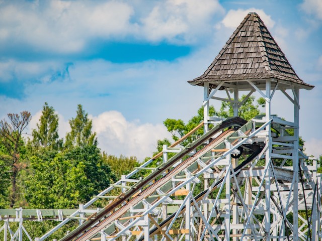 White wooden roller coaster with hut at top of track