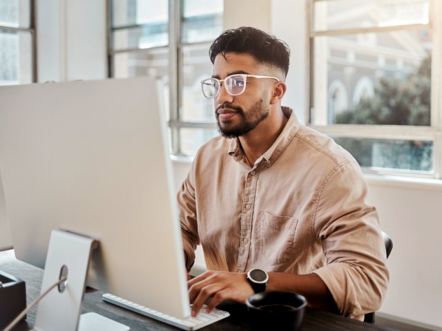 Man seated at desk looking at computer screen