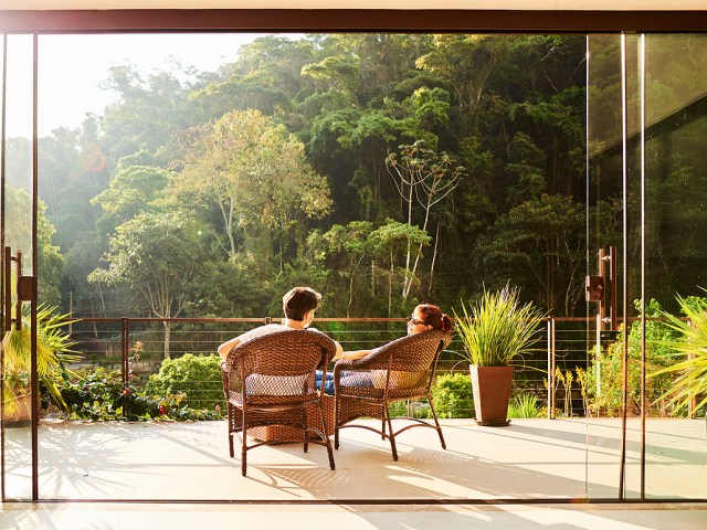 Couple on patio overlooking forest, seen from behind