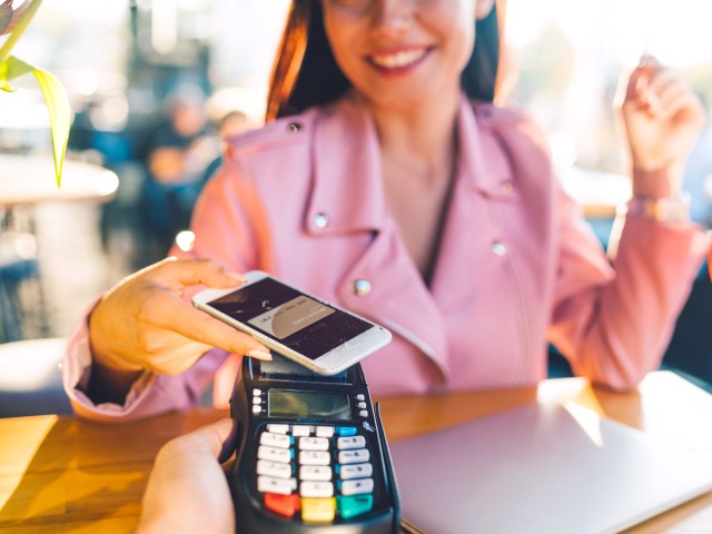 Close-up of credit card machine as customer uses phone to pay