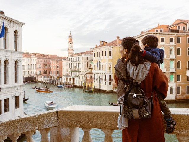 Mother carrying child and overlooking canals of Venice, Italy